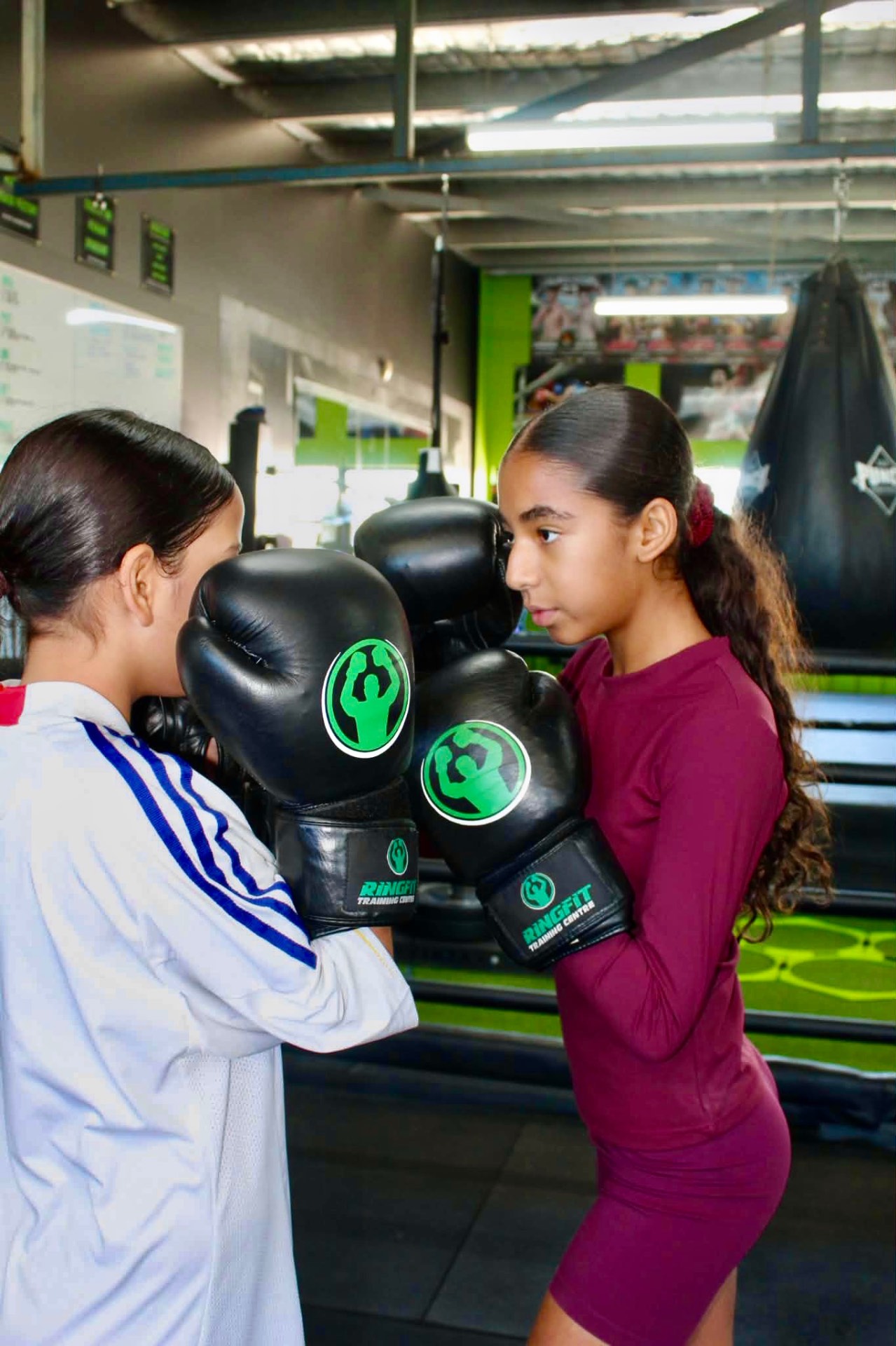 Two young female boxers touching gloves before sparring